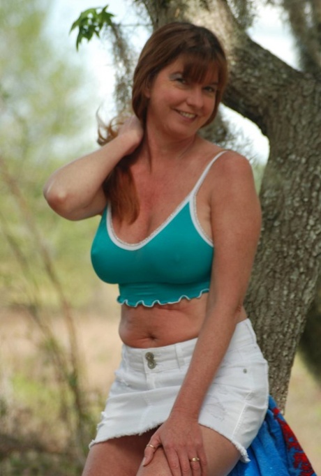 Mature lady Dee Delmar pets her snatch after stripping in the woods
