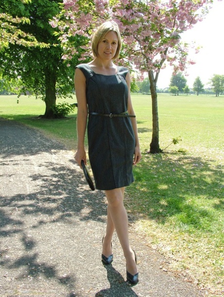 Clothed business woman shows off her sexy legs in high heels in the park