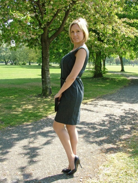 Clothed business woman shows off her sexy legs in high heels in the park
