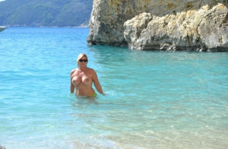 Hugely busty mature slut Chrissy swims and lounges at the beach stark naked