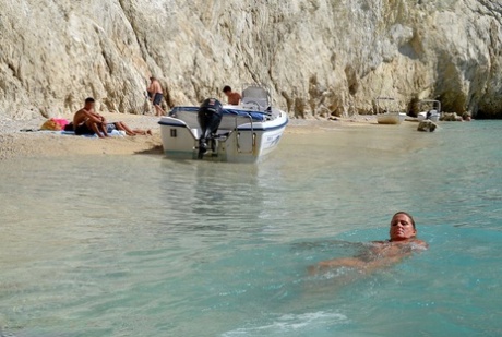 Hugely busty mature slut Chrissy swims and lounges at the beach stark naked