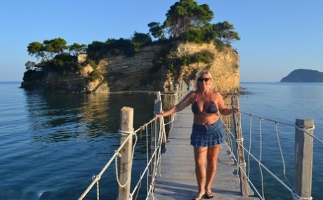 Hugely busty mature slut Chrissy swims and lounges at the beach stark naked