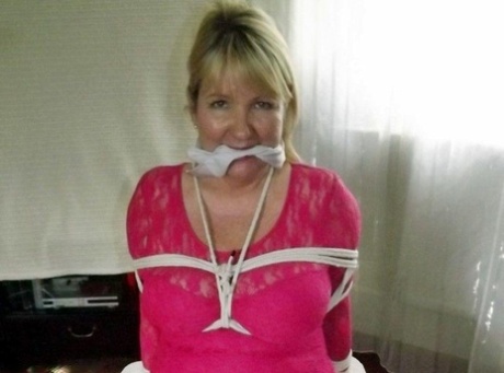 Mature lady with blonde hair ha her big naturals exposed after being tied up