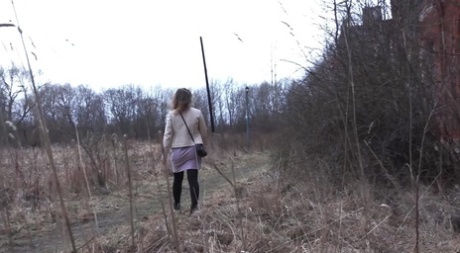 Short taken girl Rita squats for a piss behind a building in the countryside
