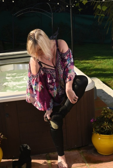 Fat older blonde Melody peels off black leggings afore an outdoor hot tub