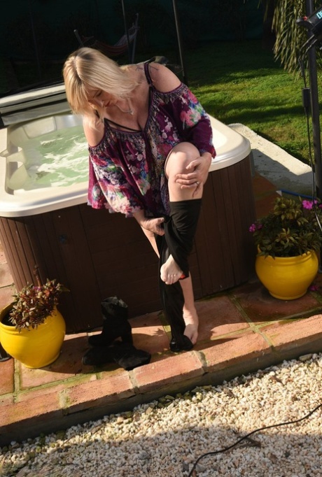 Fat older blonde Melody peels off black leggings afore an outdoor hot tub