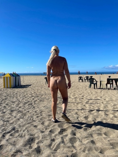 Busty blonde Sweet Susi wanders a sandy beach while naked in shades