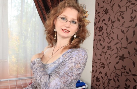 Naughty mature woman in glasses rolls of her hose to finish act of undressing