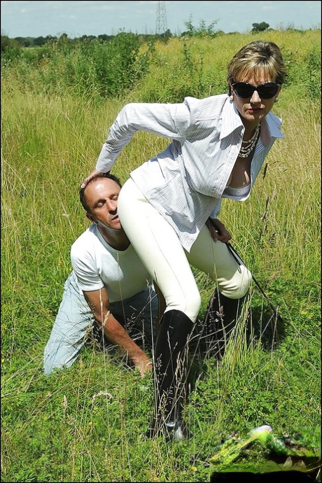 Busty mature femdom in sunglasses humiliates her boy slave outdoors